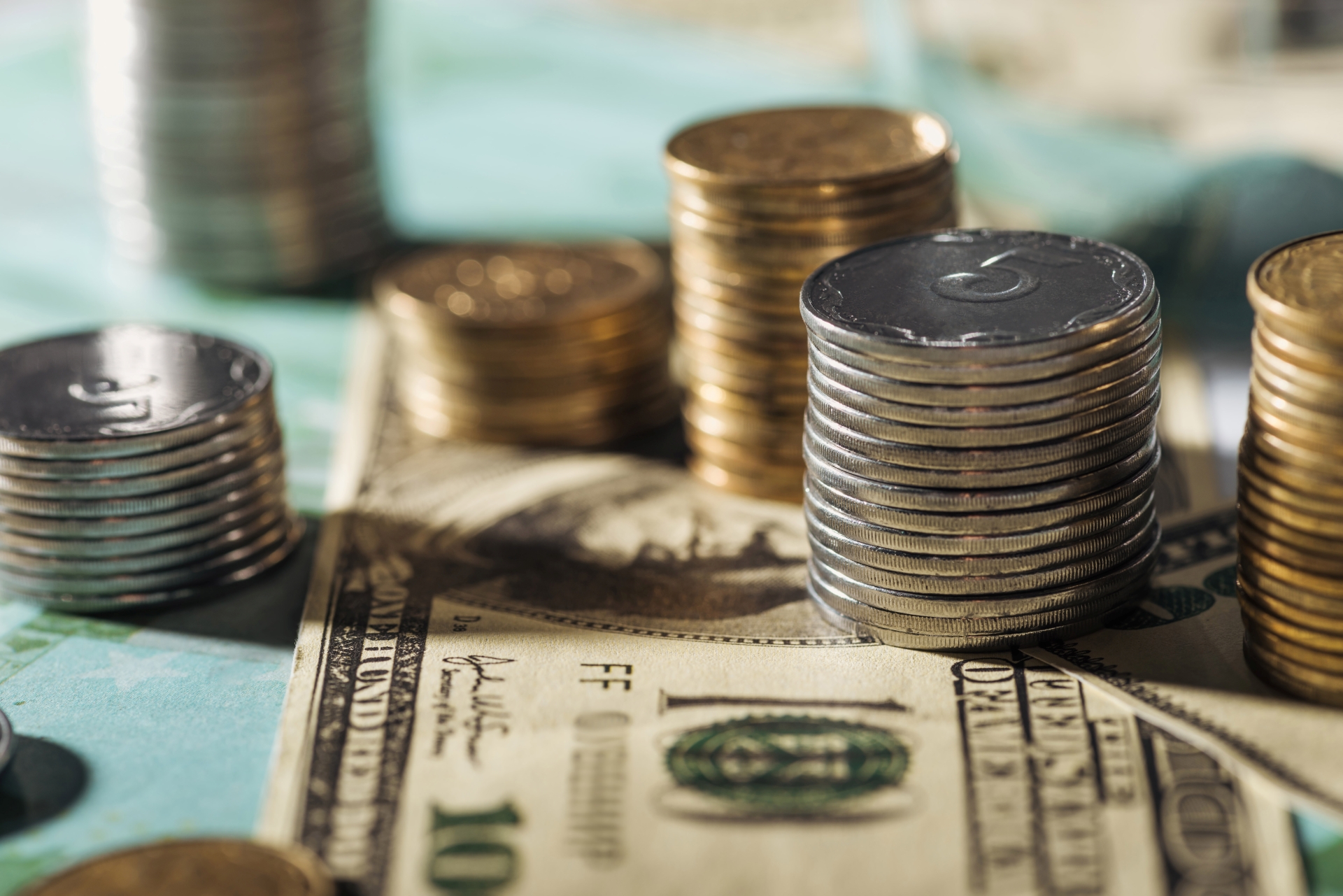 Close-up of neat stacks of silver and gold-colored coins on top of a $100 bill.