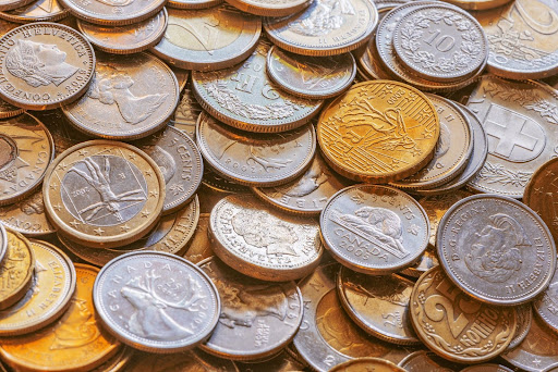 Close-up of assorted global coins, including Canadian, Swiss, and Euro currency, scattered in a vibrant pile. 