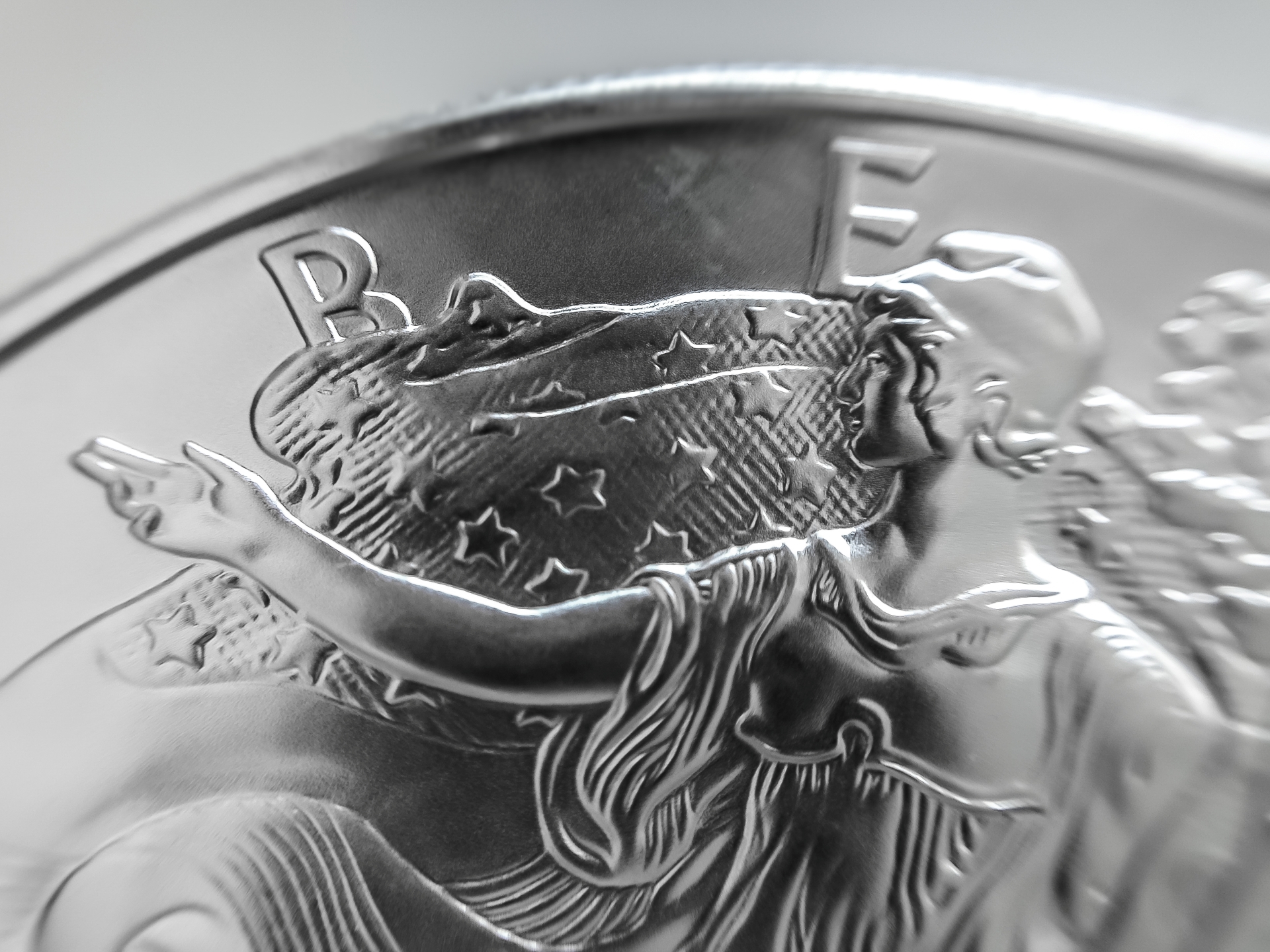 Close-up of the "Walking Liberty" design on a silver coin, highlighting the stars and stripes on the flag.