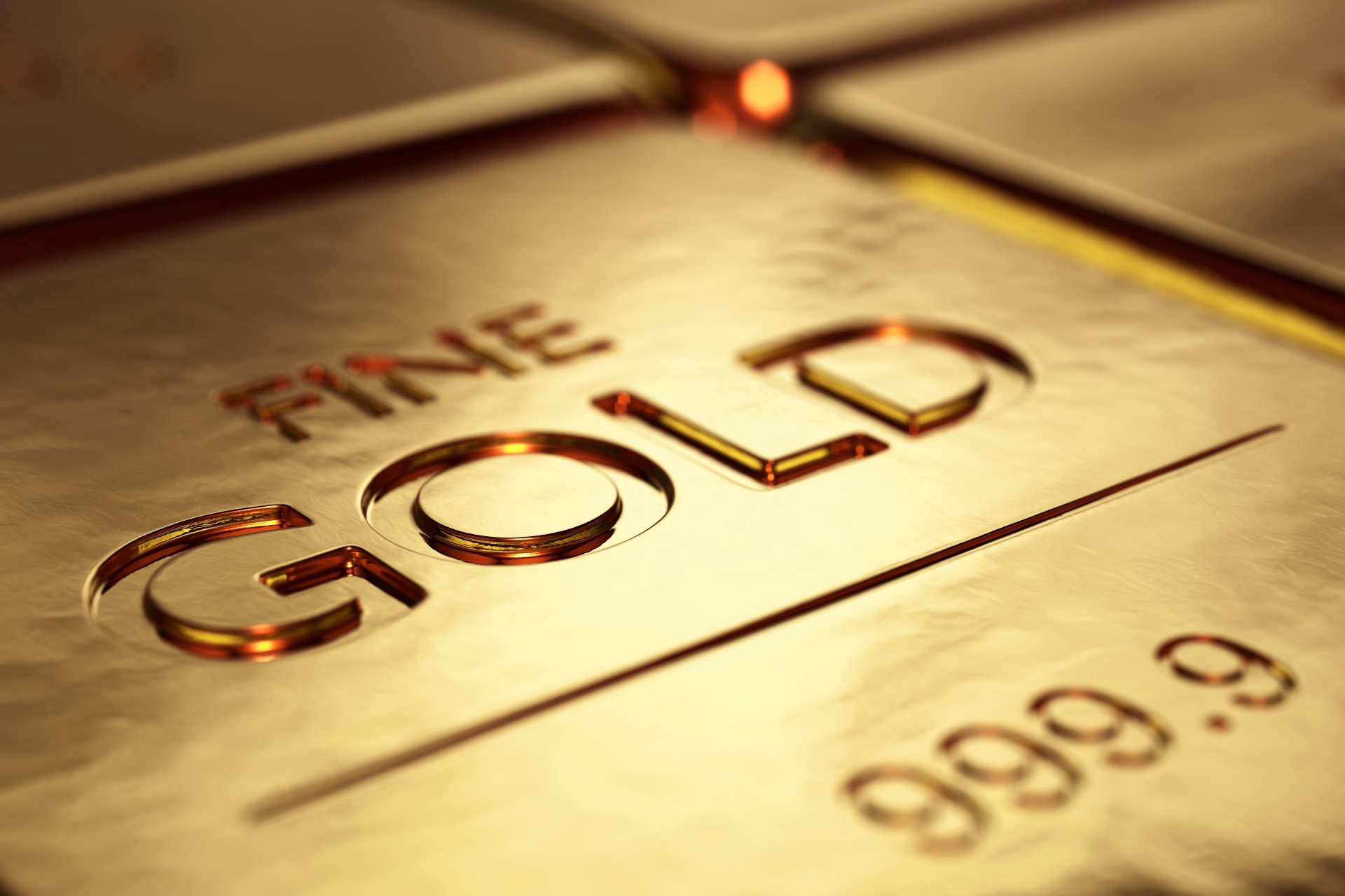Extreme close-up of a gold bullion bar stamped with "FINE GOLD" and "999.9" purity.