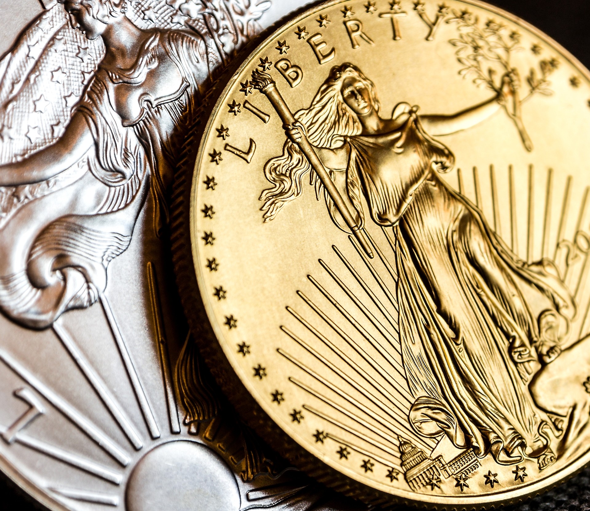 Close-up of a gold American Eagle coin partially overlapping a silver American Eagle coin.