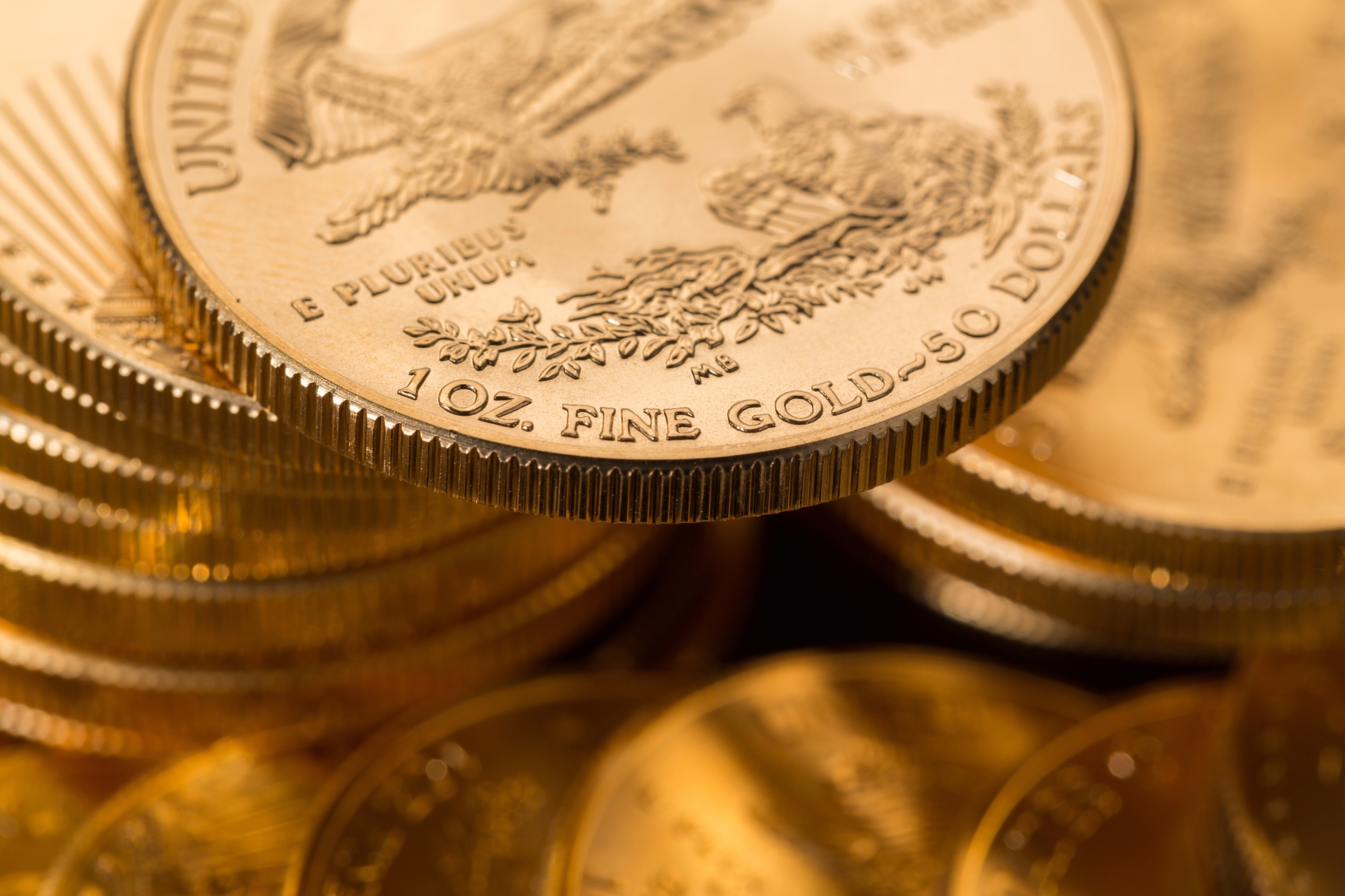  Close-up of the reverse side of a 1 oz gold American Eagle coin resting on a stack of coins.