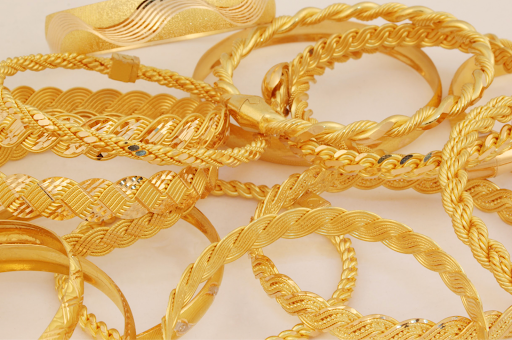 A collection of intricately designed gold bangles with textured patterns, showcasing fine craftsmanship and purity. 