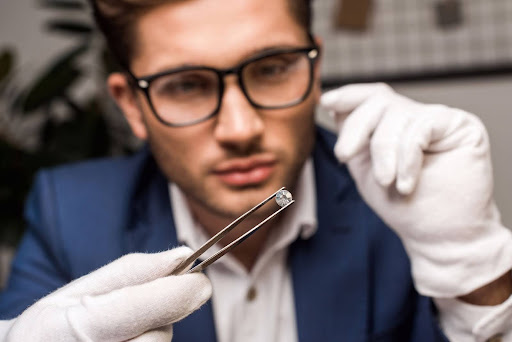 A professional jeweler wearing gloves examines a diamond with precision tweezers for clarity and quality.