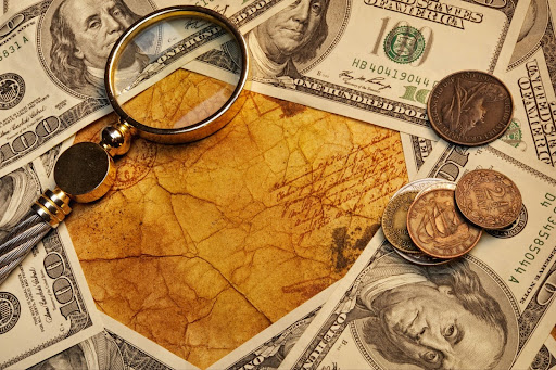 Magnifying glass, vintage coins, and $100 bills on old parchment paper with script, symbolizing wealth and history. 