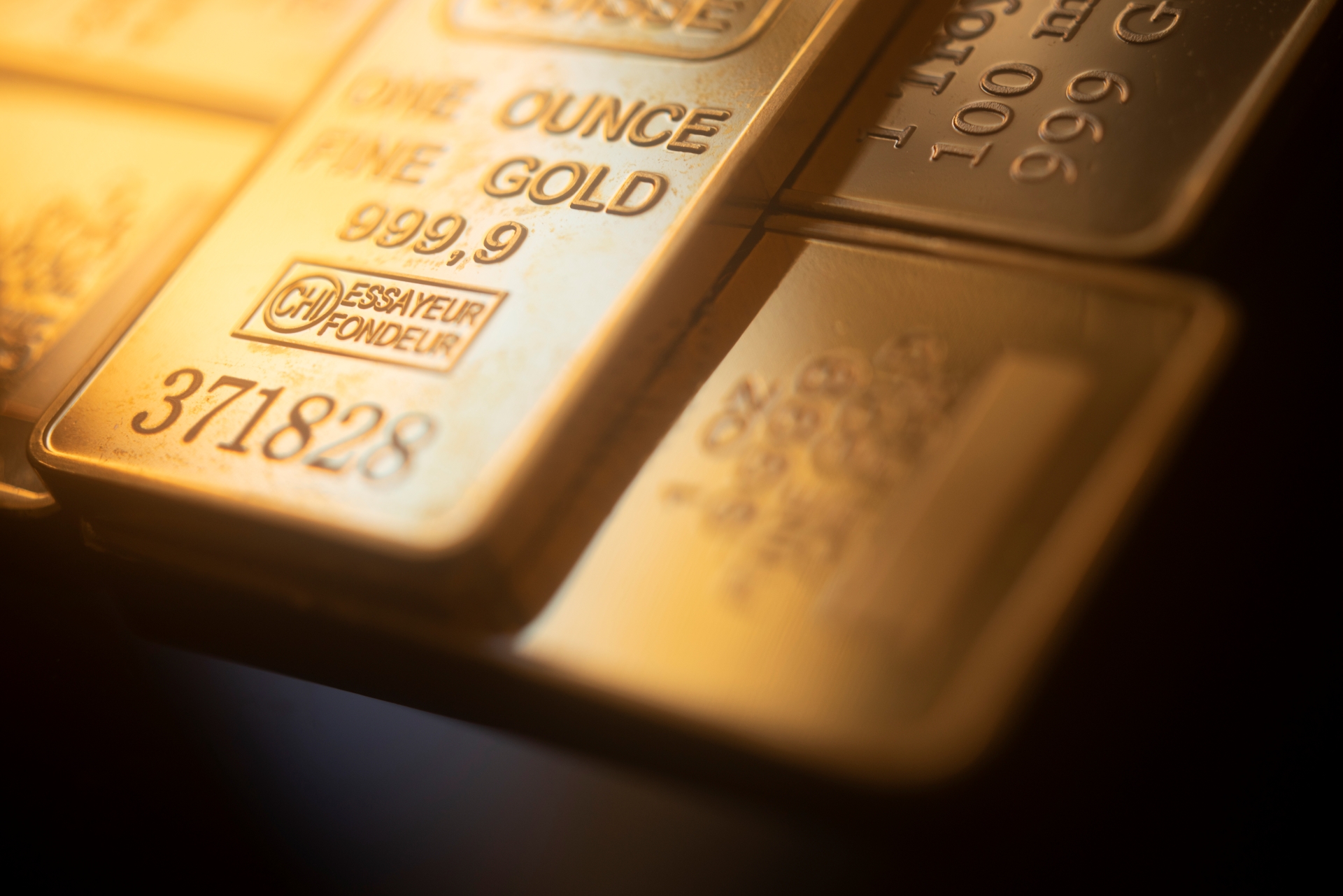 A close-up of two gold bars with visible serial numbers and the markings "ONE OUNCE FINE GOLD."