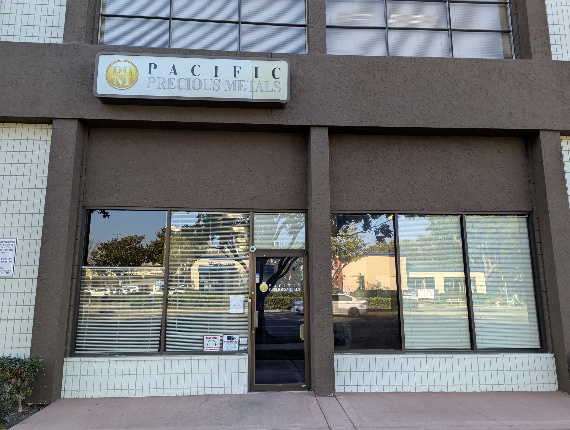  Exterior view of Pacific Precious Metals office location with large windows and branded signage above the entrance. 