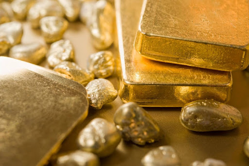 Close-up of fine gold bars and raw gold nuggets, reflecting physical precious metals investment options.