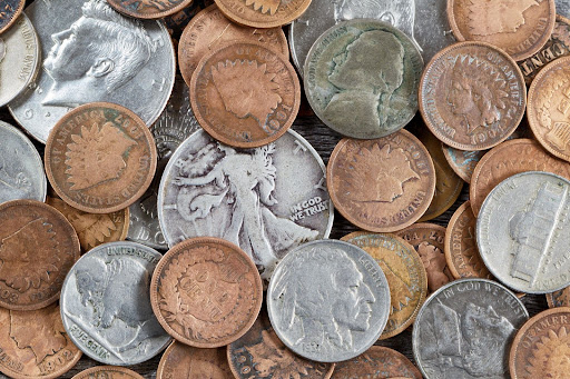 Assorted collectible U.S. coins including Indian head cents, buffalo nickels, and silver quarters in a mixed pile.